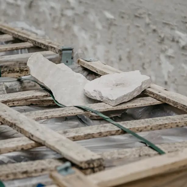 Pieces of rough-cut sandstone resting on a timber pallet on a residential building site