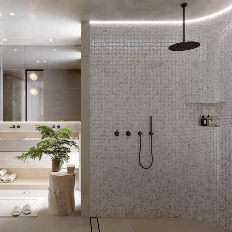 Render of a bathroom with a curved mosaic-tiled walk-in shower, stone vanity and soft concealed lighting