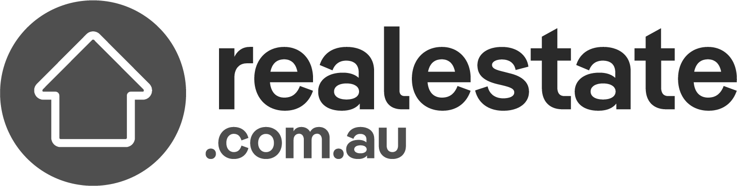 Logo of realestate.com.au, featuring a white outline of a house within a dark circular background on the left. To the right of the circle, the text "realestate.com.au" is depicted in bold, sans-serif font, embodying simplicity and modernity for those seeking the best duplex designs by renowned Sydney architects.